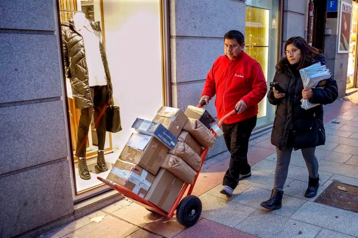 El repartidor Amado Lpez y su mujer Mnica se dirigen cargados de paquetes a la furgoneta de reparto en Madrid.
ANDREA COMAS